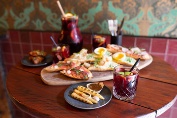 Glass of red Sangria on a table full of food with tapas platter in the background and an can of more Sangria