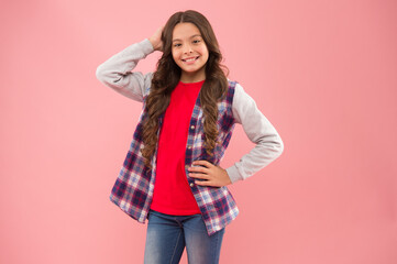 Happy childrens day. Little girl pink background copy space. Teen promoting fashion clothes. Kids fashion. Smiling school girl. Kid long curly hair. Small girl wear checkered shirt. Happy child