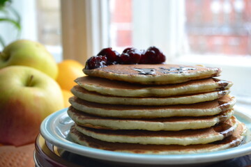 Delicious home-made pancakes with cherry syrup on plate and Yummy fruits oranges and apples....