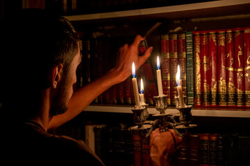 Boy holding book from the library in the dark with candles to light his way