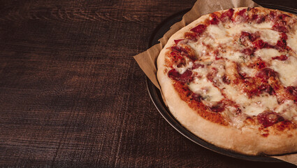 Homemade pizza with mozzarella and ham with basil. On a wooden table top.