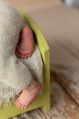 small feet of a newborn boy. the leg hangs from the edge of the crib