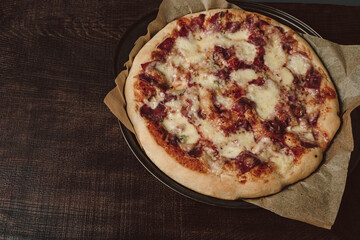 Homemade pizza with mozzarella and ham with basil. On a wooden table top.