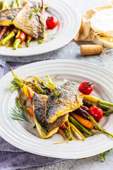 top view of delicious fish with vegetables on white plates and wine glasses on grey surface