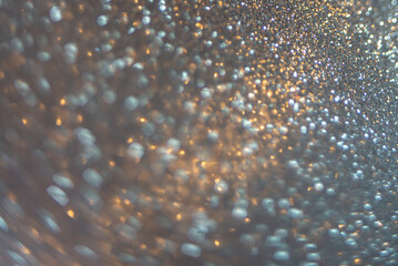 Close-up abstract unfocused background shiny texture photo glitter in a Golden-blue hue. Selective focus with bokeh light.