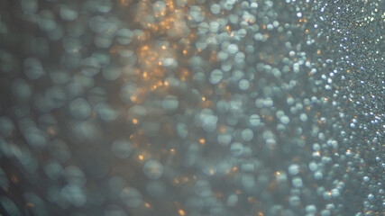 Close-up abstract unfocused background shiny texture photo glitter in a Golden-blue hue. Selective focus with bokeh light.