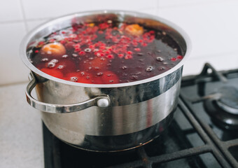 Cooking a delicious compote of apricot, apples, cherries, raspberries. Fresh fruits are boiled in boiling water in a metal pan on the stove. Photography, concept.