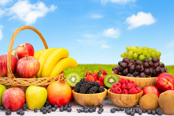 Naklejka na ściany i meble Group Healthy fresh fruit in a wooden basket, With vitamins c from bananas, kiwi, grapes, raspberries, blueberries, and blackberries, good for the body and diet food on the table in nature background.