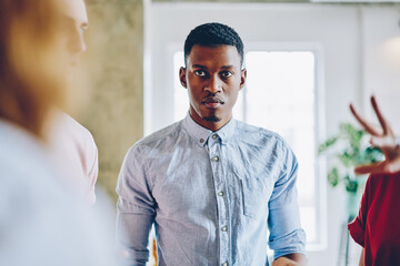 Tense stern black man in shirt looking at partner with challenge