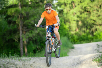 teenager in sunglasses on a bicycle rolls off a hill