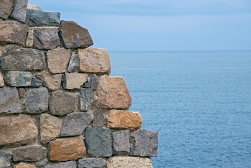 Fragments of old buildings against the backdrop of a cloudy summer sky and sea.