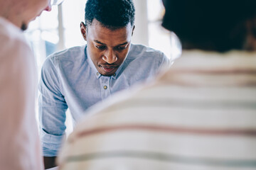 Serious black man standing at table in office