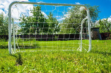 Mini football goal on the green grass on a plot near the house. Family play
