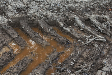 Traces of the tread of a tractor or truck on wet soft ground with water. Construction machinery at work in the forest.
