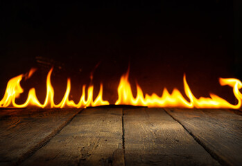 Aged empty wooden table in front on a fire flame background. Table in perspective view with copy...