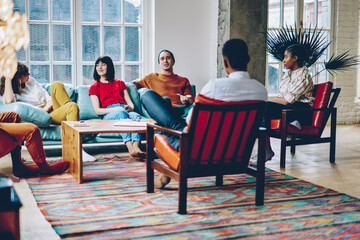 Group of delighted multiethnic friends chatting at home