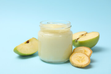 Glass jar with apple puree on blue background, close up