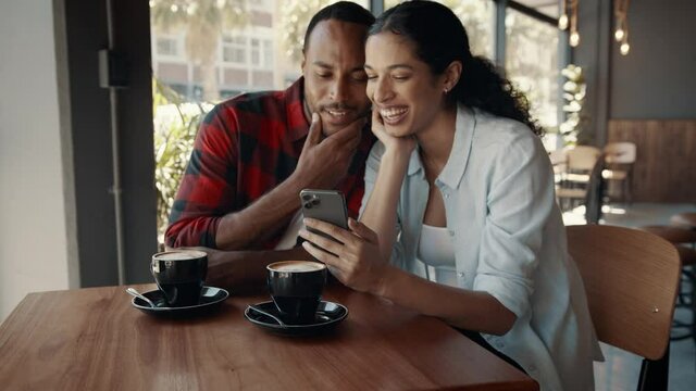 Happy young couple enjoying dating in a coffee shop. Man and woman talking and smiling while sitting at a cafe table. 
