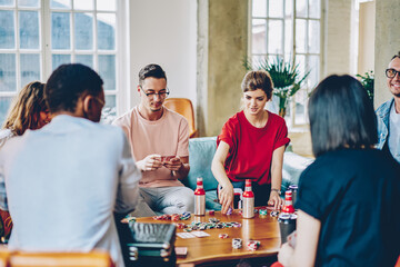 Focused multiethnic group of people gambling in cards on weekend in apartment