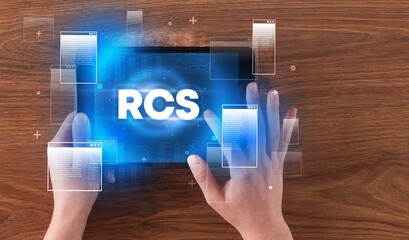 Close-up of a hand holding tablet with RCS abbreviation, modern technology concept