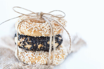 Obraz na płótnie Canvas Three salty cookies with sesame and black cumin on a hessian texture in front of the white background, close up