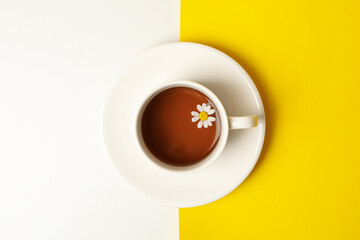 Cup of chamomile tea on two tone background, top view
