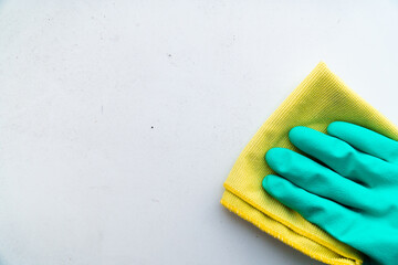 hand in green rubber glove wipes dusty table with a rag