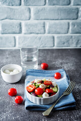 Mozzarella cucumber tomato red onion salad in a white bowl
