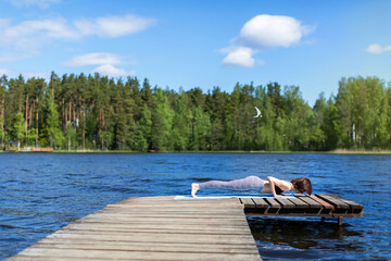 Young woman practicing yoga, doing four limbed staff, Push ups or press ups exercise, chaturanga dandasana pose, working out, wearing sportswear. outdoors nature background. Sunny day on lake