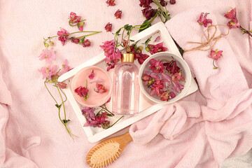 Spa and wellness composition with fragrant water of pink flowers in a wooden bowl, aromatherapy with rose water and body cream and skin and body care, flat lay, lifestyle concept