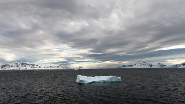 An Iceberg free-floating in the Gerlache Strait, Antarctica. Land features in the background are Lemaire Island on the left and Bryde  Island on the right. Camera handheld from a moving vessel.