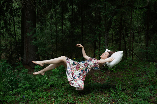 Levitation portrait of young woman dreaming in the woods.