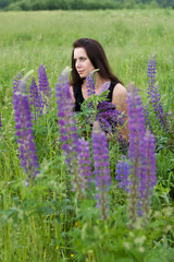 Girl sitting in a meadow. Among the blooming lupine.