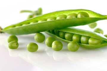 Pods of green peas with pea leaves and flowersd on a white background. Organic food.