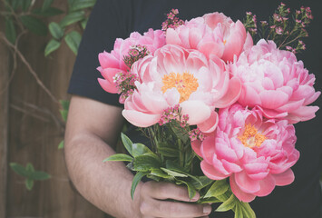 Man presents beautiful pink peonies  outdoors