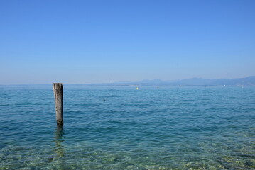 Holzpfahl im Wasser als Anlegestelle für Boote und Schiffe am Gardasee in den Sommermonaten
