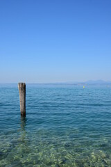 Holzpfahl im Wasser als Anlegestelle für Boote und Schiffe am Gardasee in den Sommermonaten