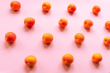 Orange apricots scattered on a pink table. Healthy food concept, top view