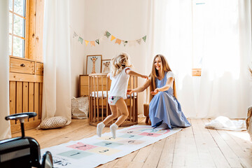 Young mom or babysitter playing with little girl at home