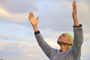 man praying looking up to the sky with arms outstretched Caribbean man praying  stock photo