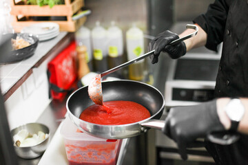 A process of cooking tomato pasta in a restaurant kitchen. Fresh made pasta on a pan