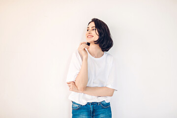 Lifestyle portrait of a happy young woman having fun on a white wall background