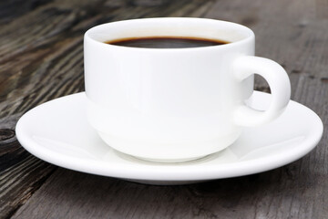 A cup of coffee and on a grey wooden background. White coffee cup and saucer.Copy space. Place for text