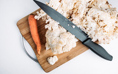 Hericium erinaceus or Lions mane mushroom with kitchen knife and carrot.