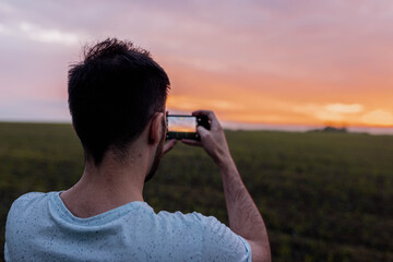 man photographs the sunset on the nature with a smartphone.