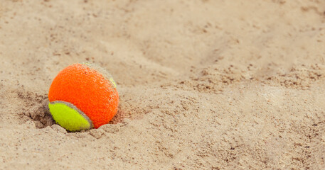tennis ball on the sand at the beach close up