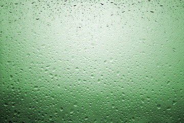Drops of rain on a window glass with very diffuse landscape emerald green color