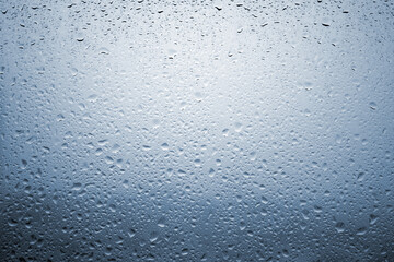 Drops of rain on a window glass with very diffuse landscape cobalt blue color