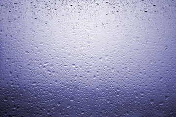 Drops of rain on a window glass with very diffuse landscape navy blue color