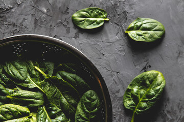 Fresh mini spinach in a colander on the old concrete table. Healthy food, eco product. Vegan